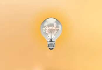 Light blub with the word "goal" in the middle of it, on a muted yellow background.